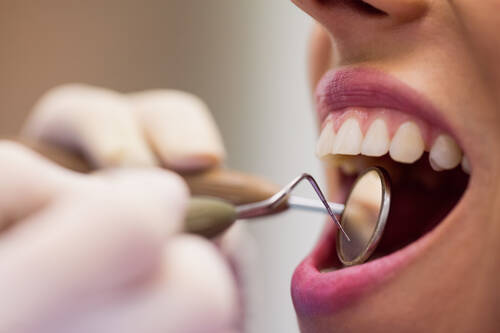 Dentist examining female patient with tools